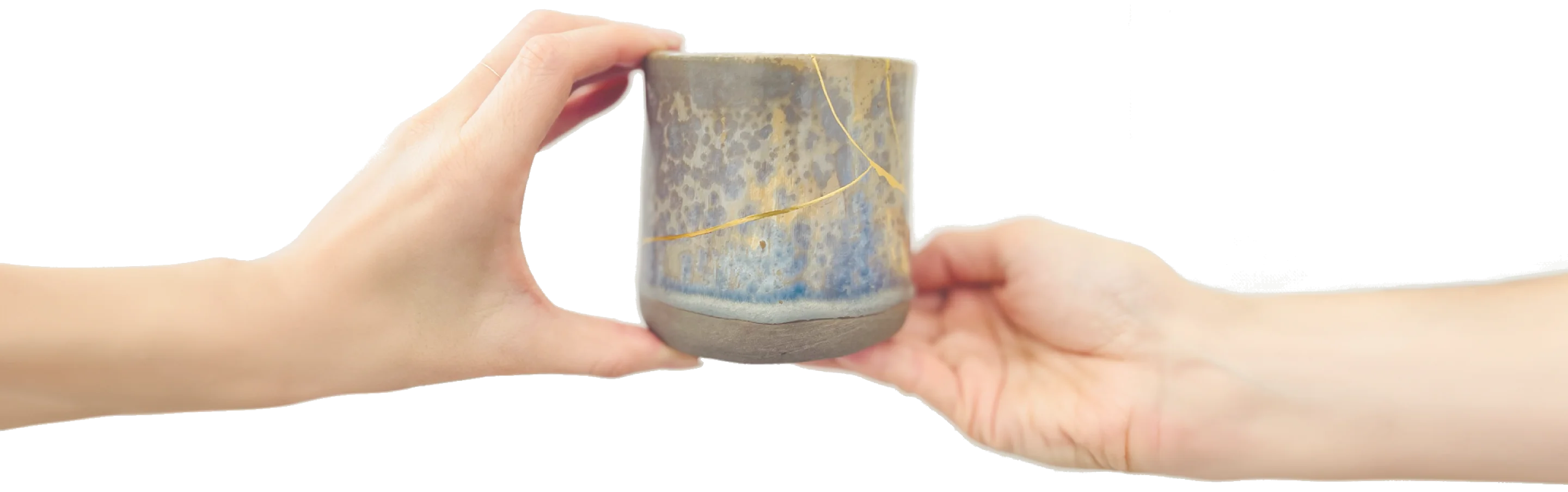 Two hands passing a blue-grey cup mended with a gold seam.