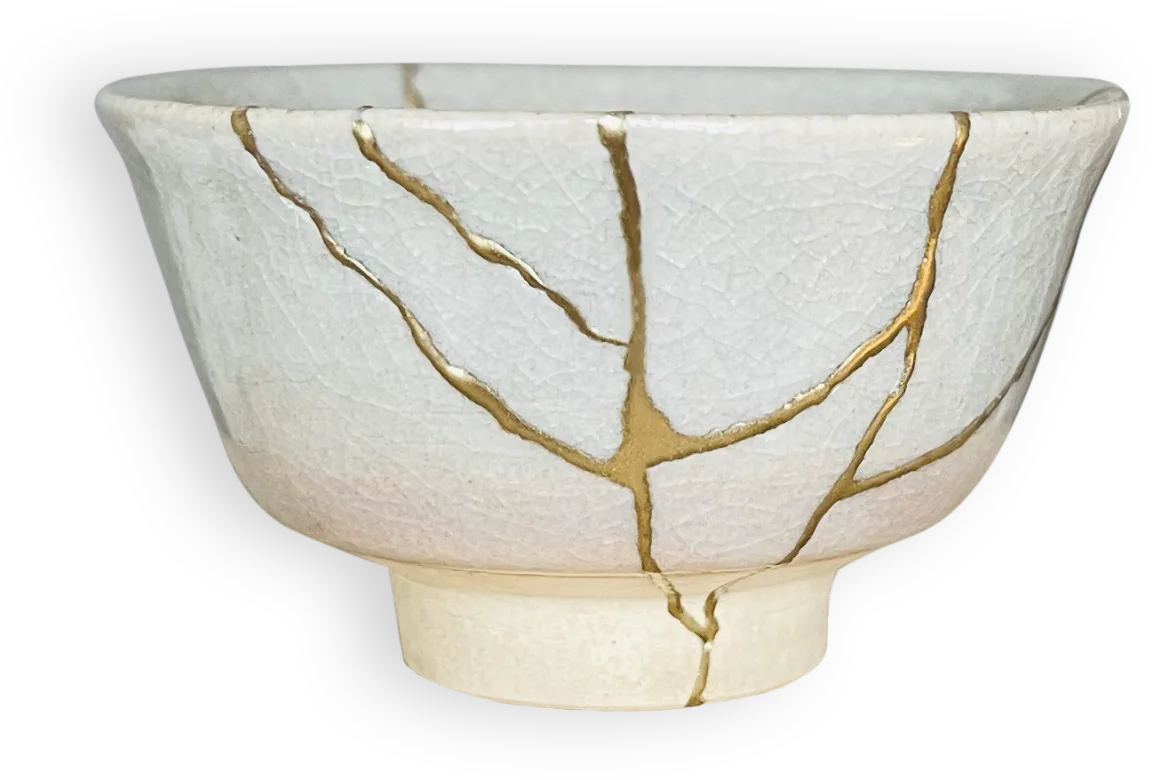 A pale ceramic tea bowl repaired with branching seams of gold.