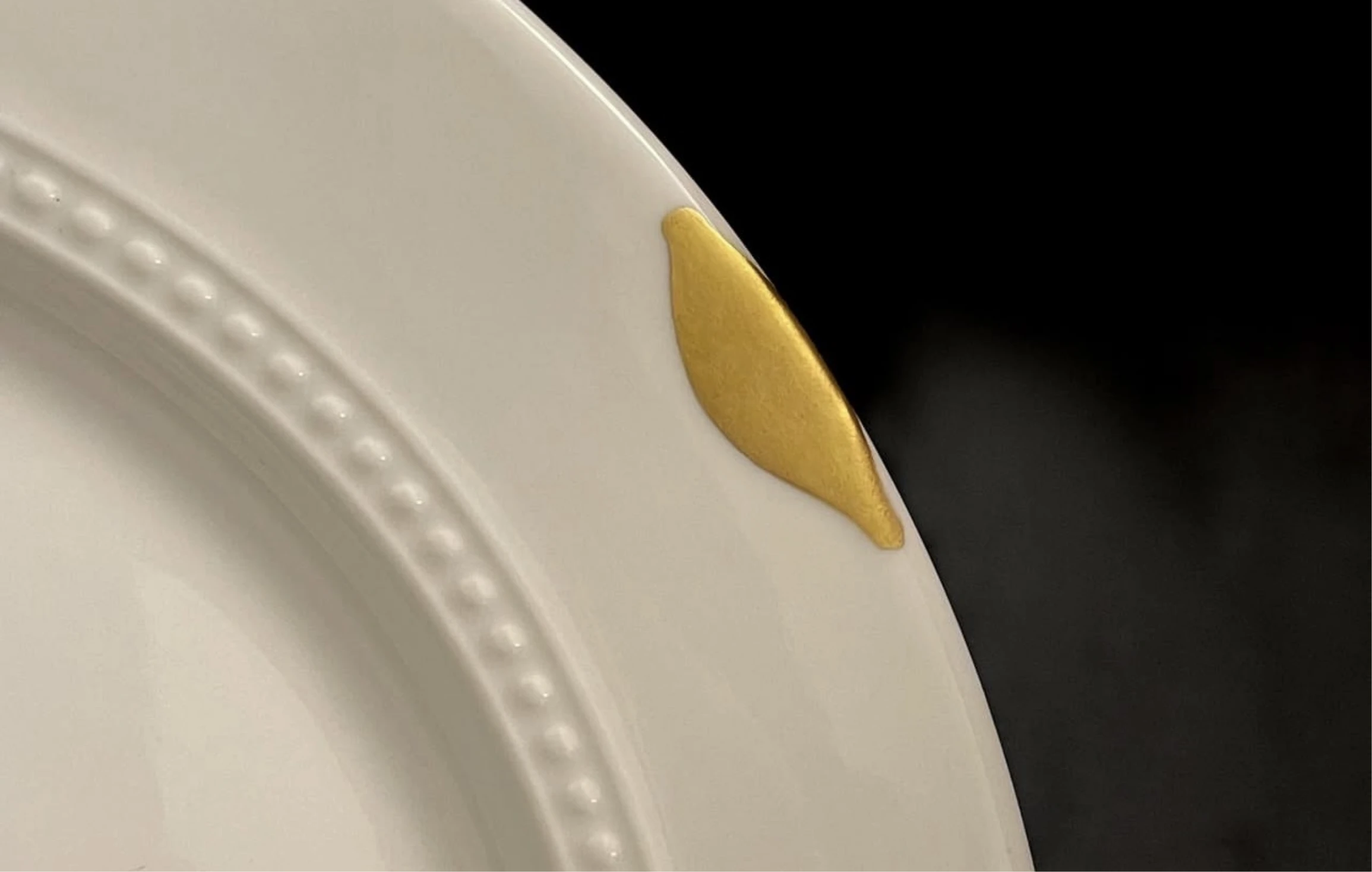 A white beaded-rim plate with a gold-filled repair.